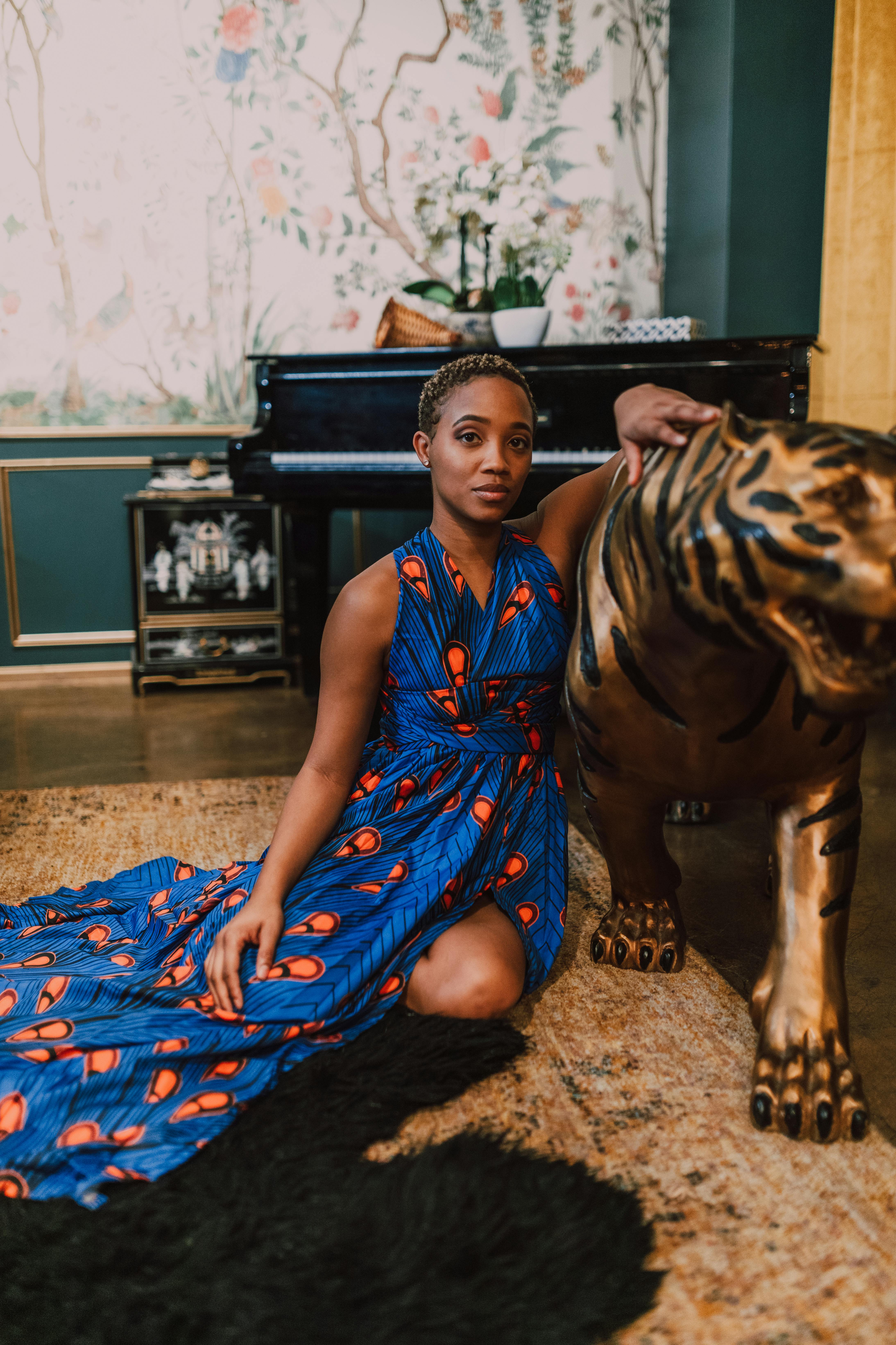 woman in blue and brown dress sitting beside tiger statue