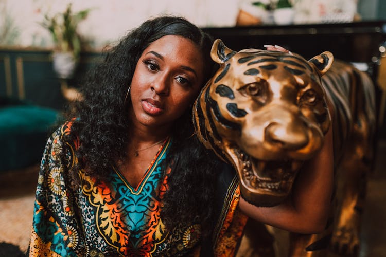 Close-up View Of A Woman Sitting Beside A Tiger Statue