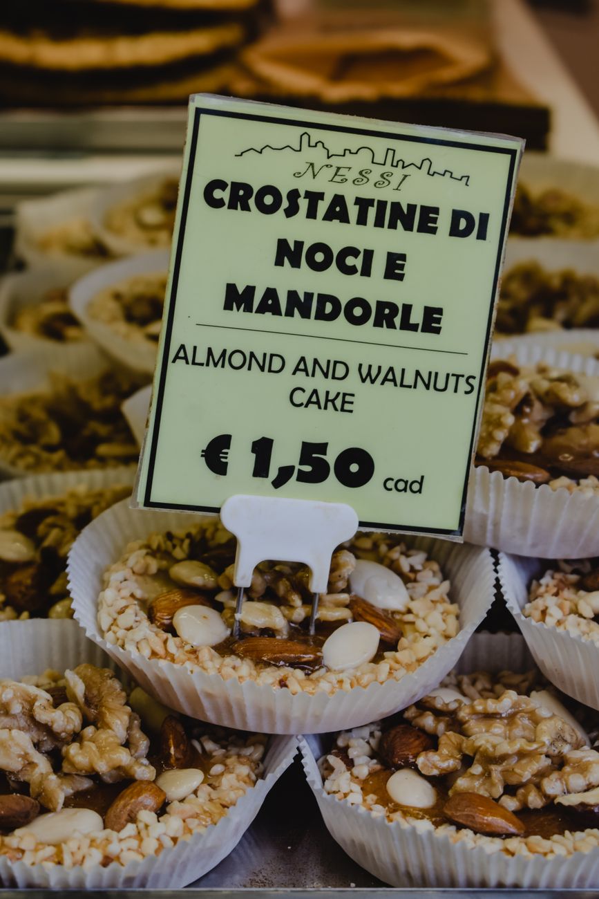 Nahaufnahme von Mandel- und Walnusskuchen in einer italienischen Bäckerei mit Preisschild.