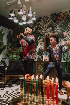 Festive Kwanzaa scene showcasing cultural dance and vibrant traditional clothing indoors.