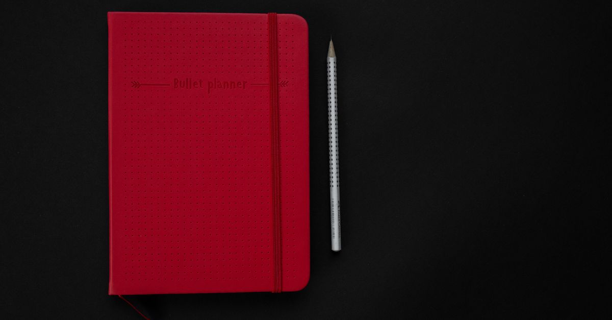 Planner and pen on a dark desk