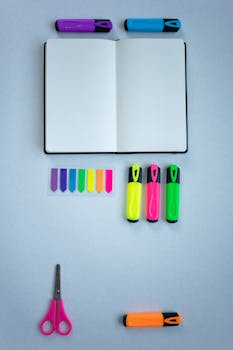 Organized flat lay of colorful office supplies on a light blue background.