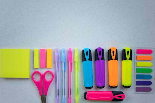 Flat lay of colorful school supplies including pens and highlighters on a white surface.