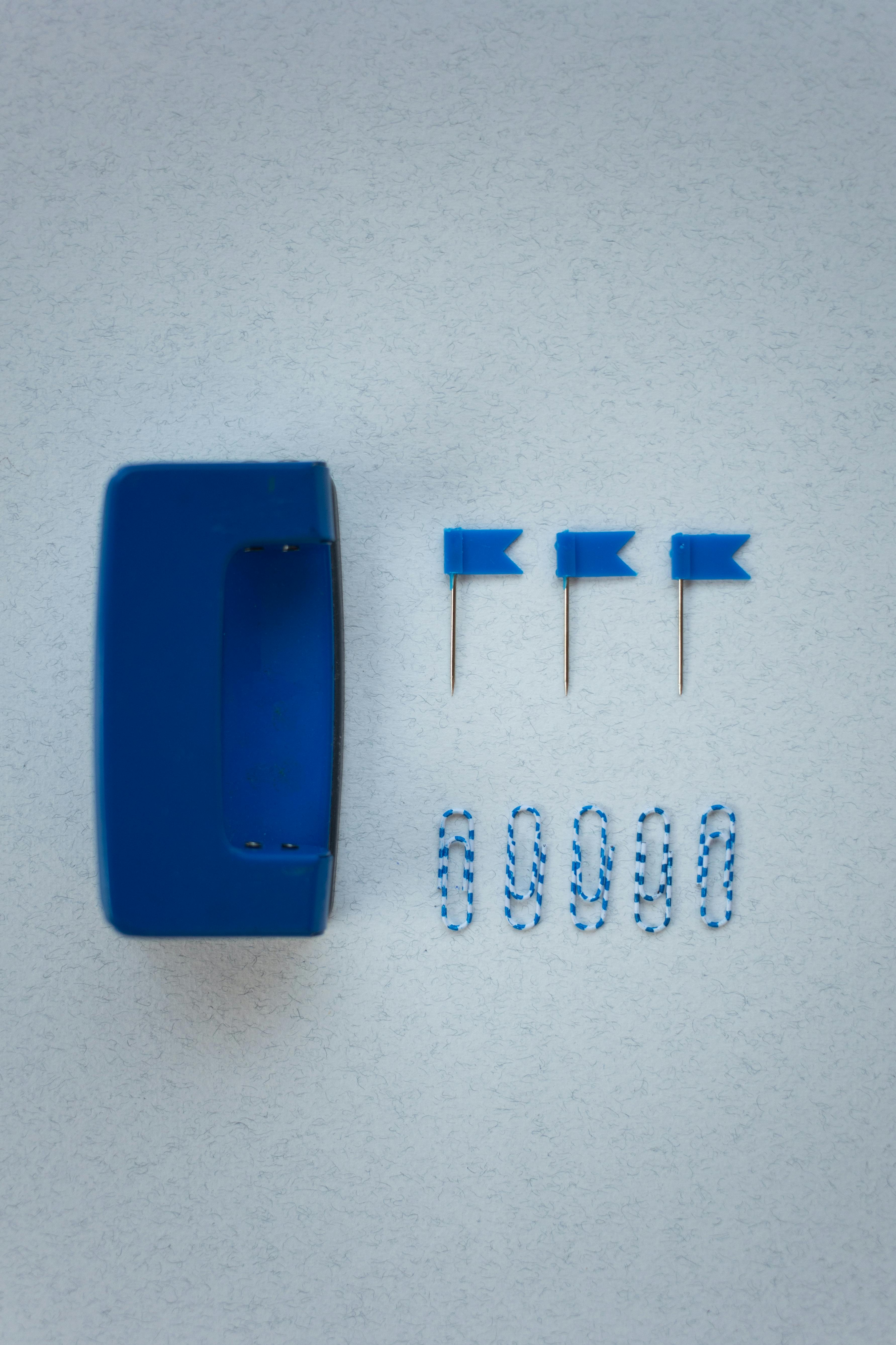 paper clips and pins beside a hole puncher