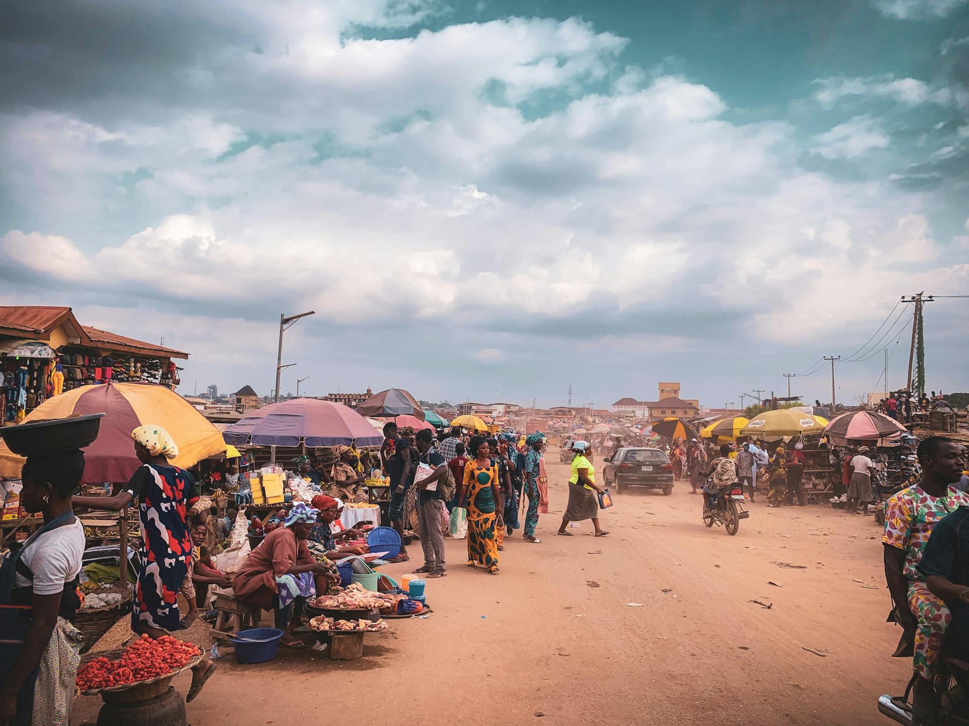 Bustling outdoor market scene in Africa with colorful umbrellas and active local commerce.