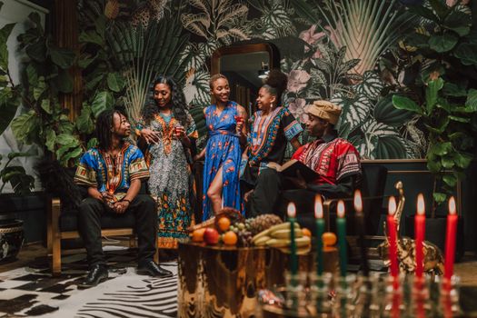 Group celebrating Kwanzaa in traditional dashikis and kaftans, surrounded by festive decor.