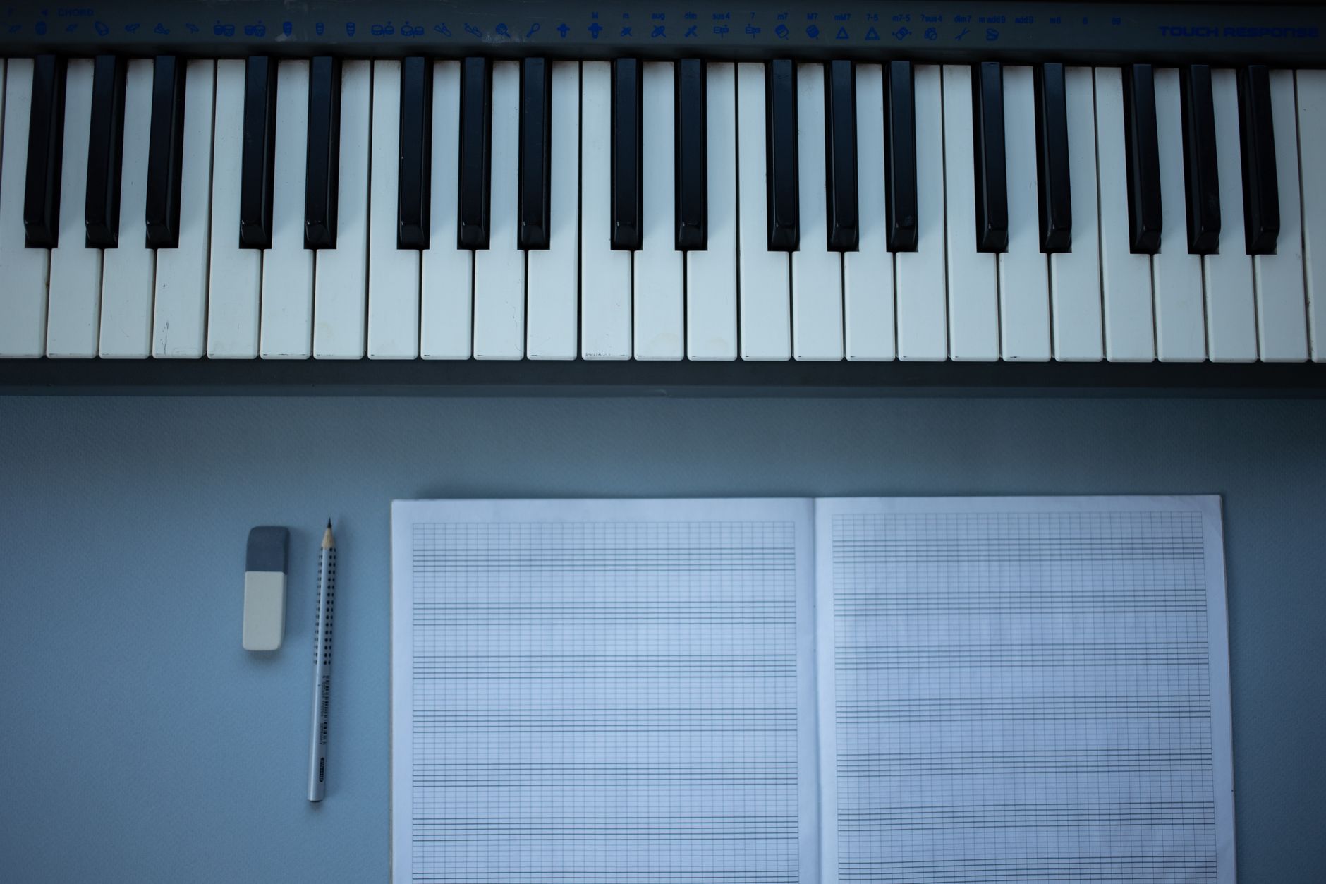 Flat lay of piano keys, sheet music, pencil, and eraser for music composition.