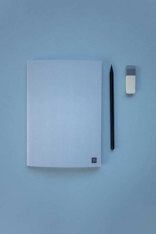 Free Top view of a notebook, pencil, and eraser on a pastel blue background in a minimalist style. Stock Photo