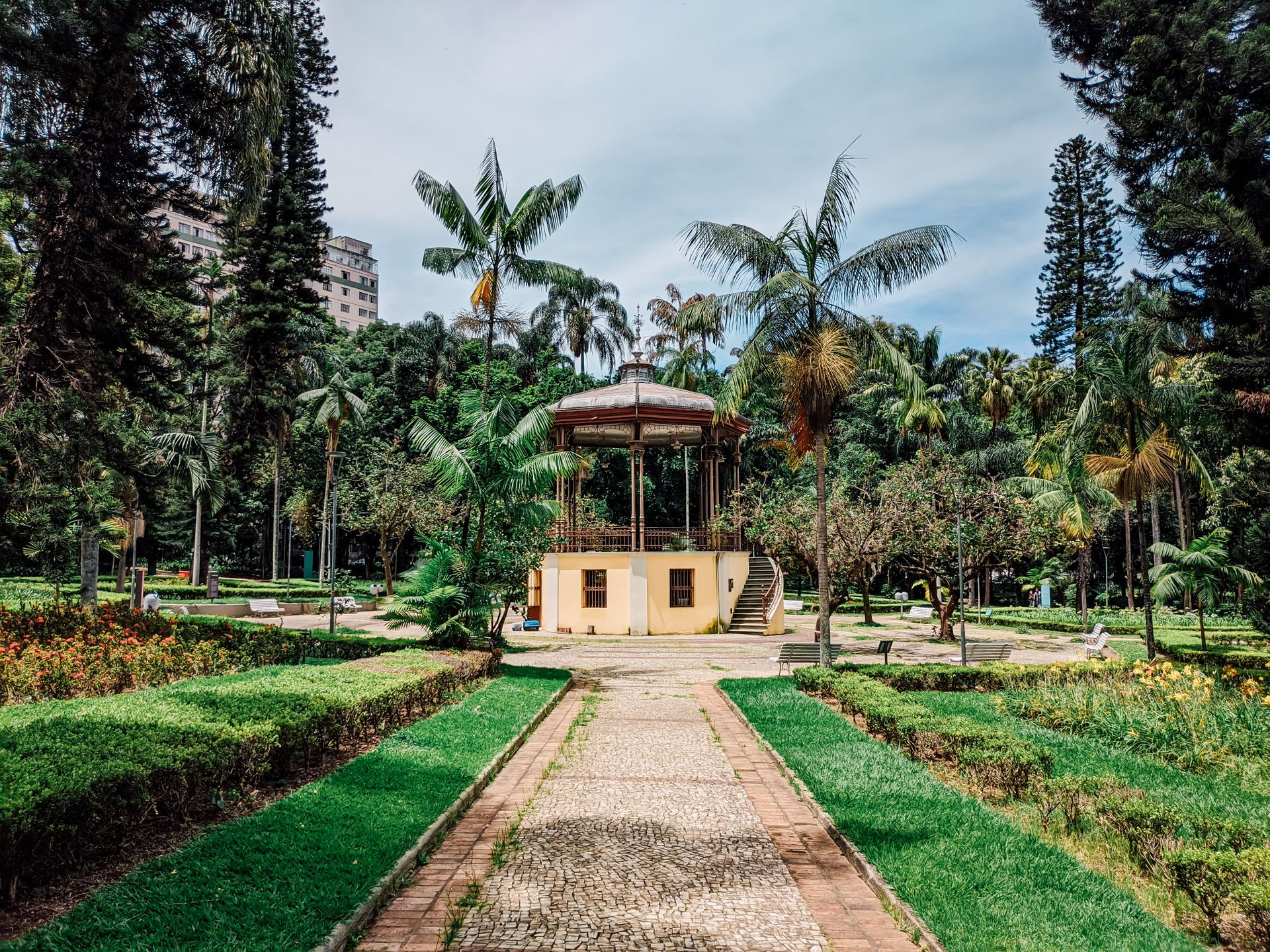 Beautiful park with a central gazebo surrounded by lush palm trees and vibrant gardens.