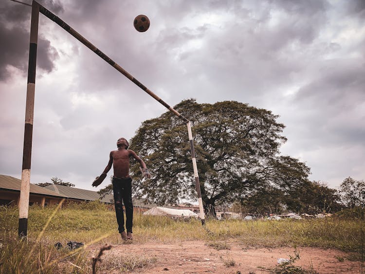 Kid Playing Football On Grass Field