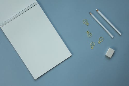 Free Spiral Notebook and Pencils on a Blue Surface Stock Photo