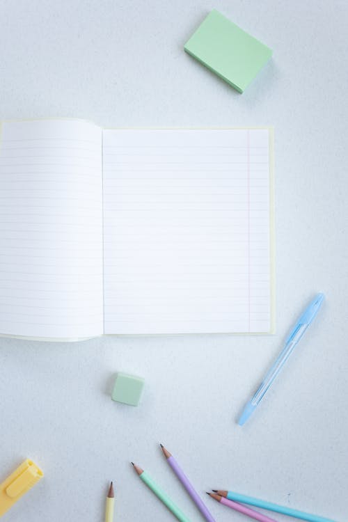 Free A Notebook and Coloring Materials on a White Surface Stock Photo