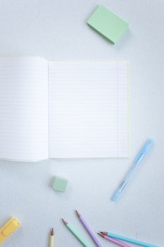 A Notebook and Coloring Materials on a White Surface