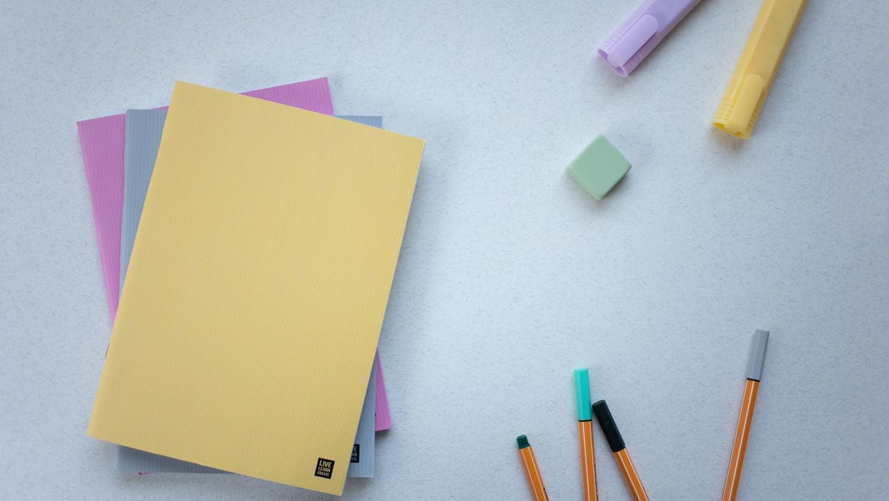 An assortment of multicolored highlighters and stationery on a white table.