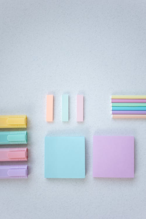 Colorful Sticky Notes Between Markers and Pencils on White Surface