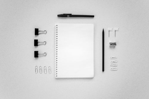 Free A minimalist arrangement of stationery items on a white surface in a flat lay style. Stock Photo