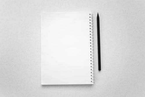 Free A Pen and a Spiral Notebook on a White Surface Stock Photo