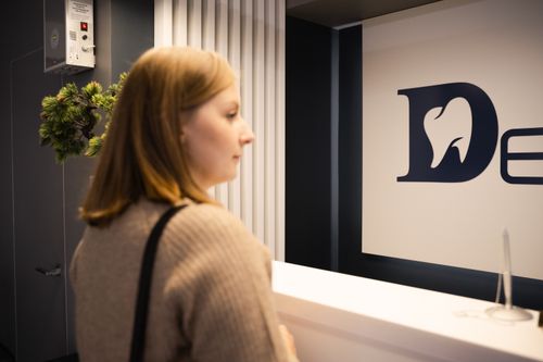 Free Young woman stands at a dental office reception, side view, casual attire. Stock Photo