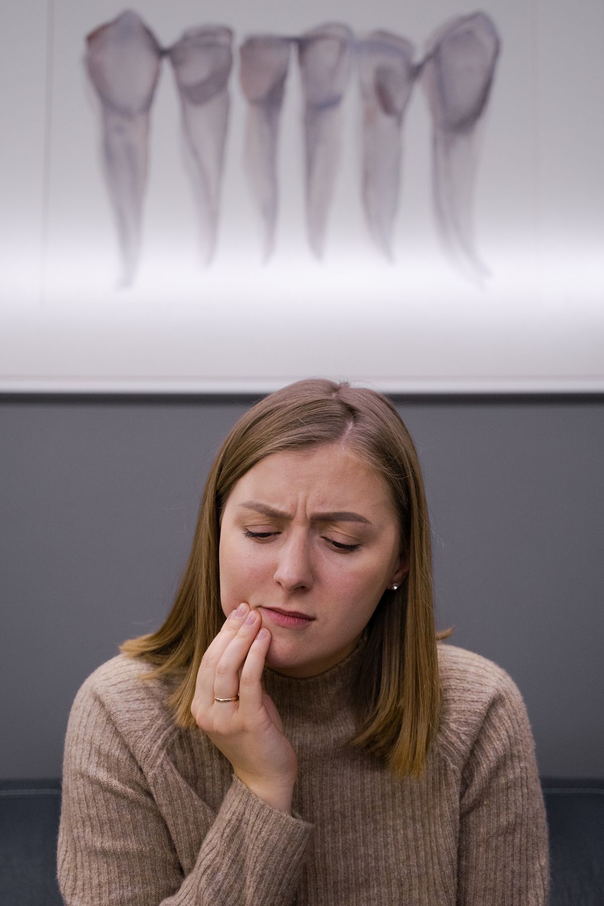 Woman holding her cheek in discomfort from jaw and TMJ pain