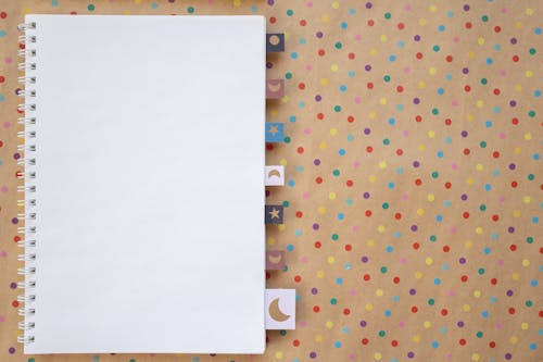 Free White Spiral Notebook on a Polka Dot Background Stock Photo
