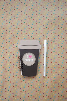 A charming coffee-themed notebook and pen on a vibrant polka dot backdrop.