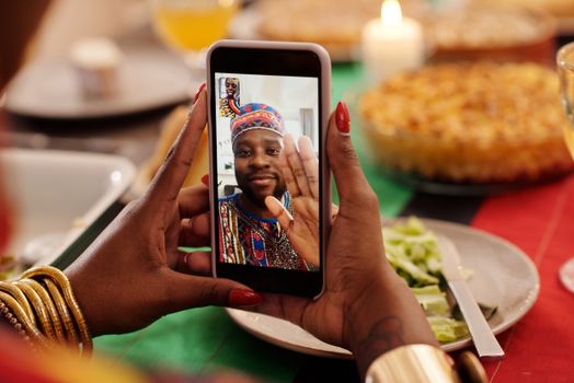 A person uses a smartphone for a festive video call during a Kwanzaa celebration.