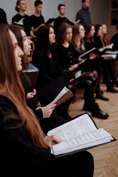 A Choir Singing while Holding Their Music Sheets