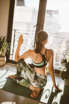 Woman in activewear performing a yoga twist in a bright indoor setting.