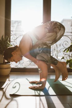 A woman performing a yoga pose indoors with sunlight streaming through a glass door.