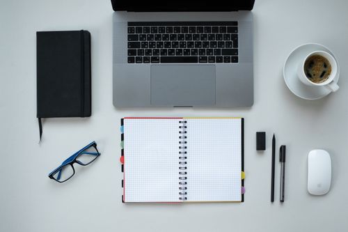 Free Top view of a desk with laptop, notebook, coffee, and office supplies, perfect for remote work theme. Stock Photo