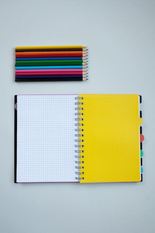 Free Colored Pencils Beside a Notebook Stock Photo