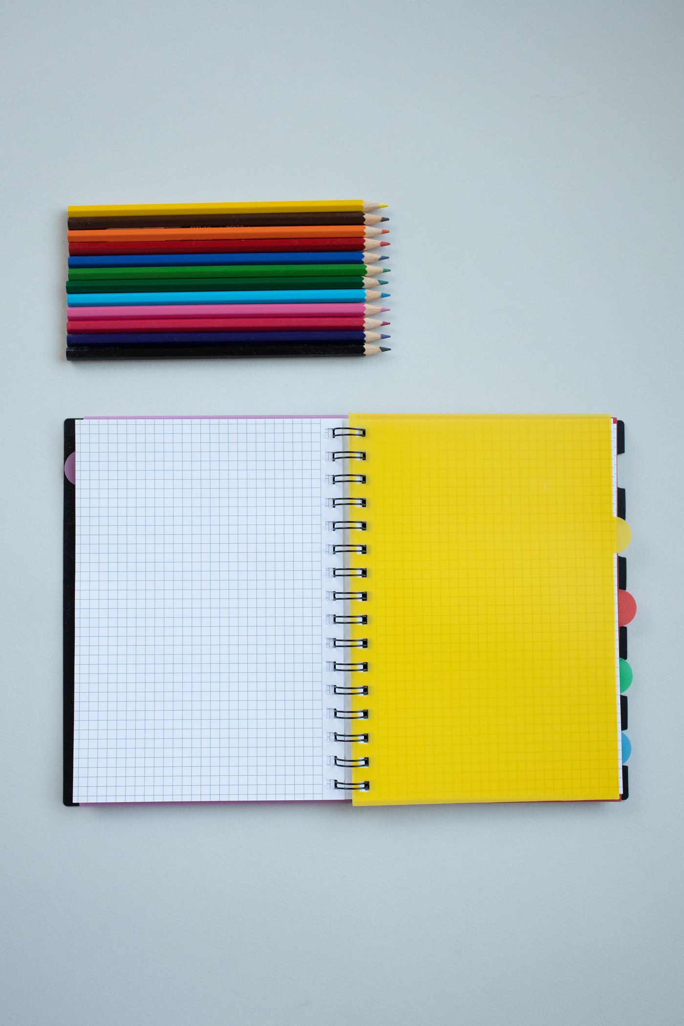 Colourful pencils beside a spiral notebook
