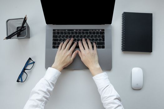 Person typing on a laptop at an office desk with accessories, emphasizing productivity.