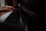 Person Playing Piano in Black Room