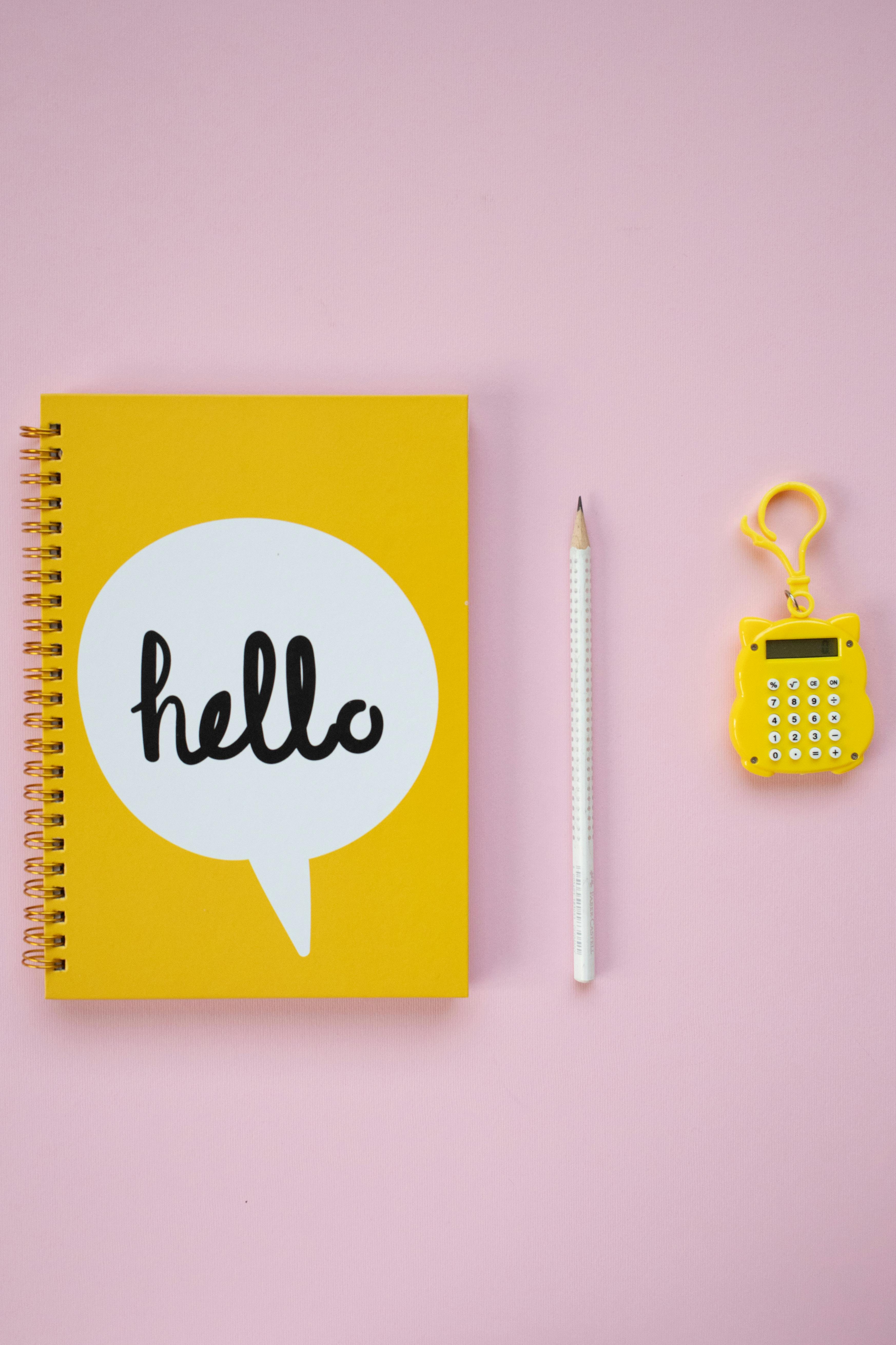 yellow and white spring notebook beside white pencil