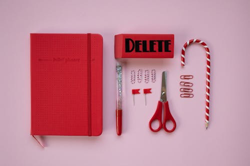 Red Notebook and Office Supplies on a Pink Surface