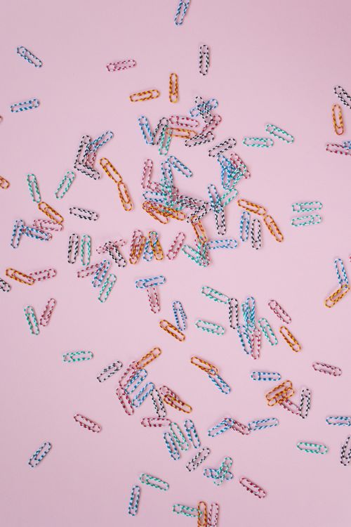 Free Vibrant scattered paper clips on a pink surface captured from above. Stock Photo
