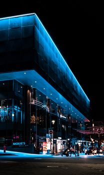 Contemporary urban bar exterior with blue walls against decorative garlands and anonymous people in evening