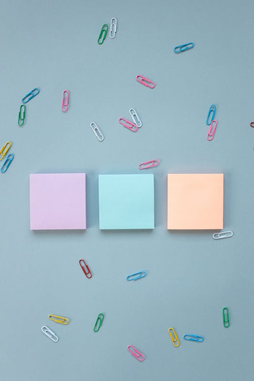 Post-it Notes and Colorful Paperclips on Blue Background