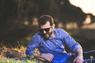 一位戴着太阳镜的时尚男士在户外休息，享受着明媚的阳光