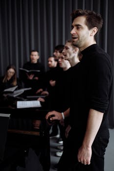 A choir group performing indoors with focus on male singer in foreground.