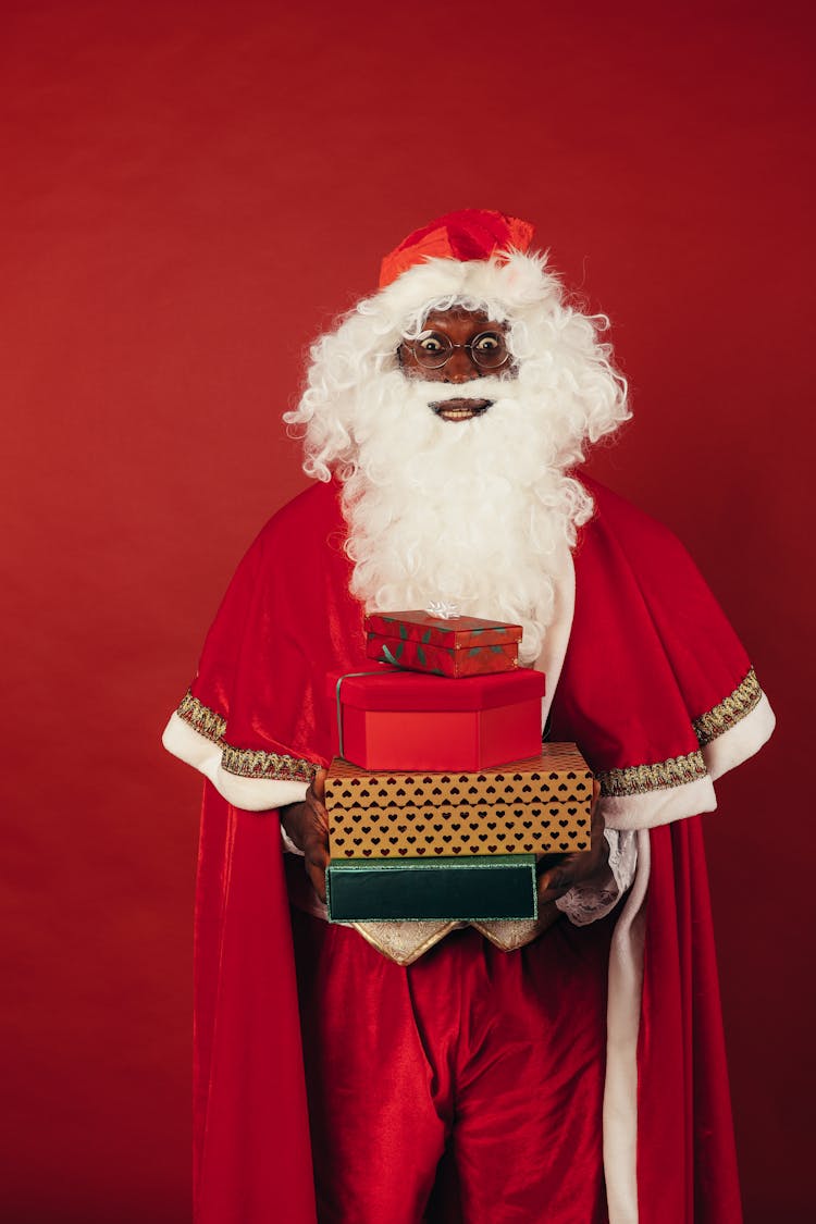 Santa Claus Holding Christmas Presents On Red Background