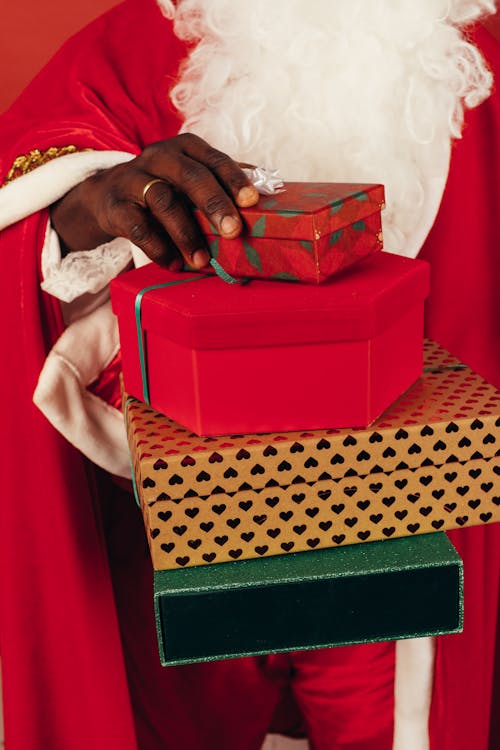 Person Wearing Santa Claus Outfit While Holding Christmas Gifts