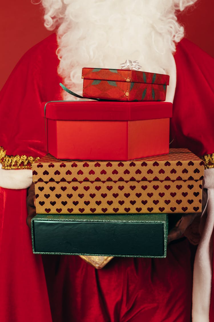 Person Wearing Santa Claus Outfit While Holding Christmas Gifts