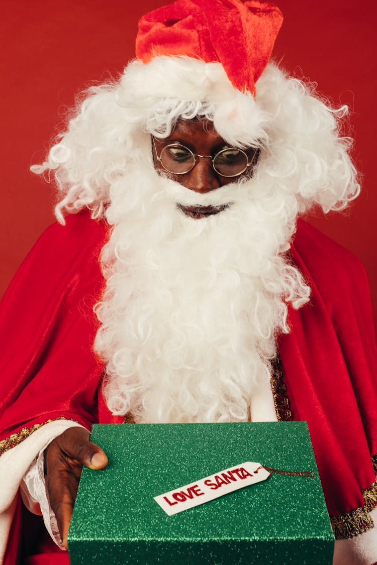 Man In Santa Claus Costume Looking Surprised At Christmas Present