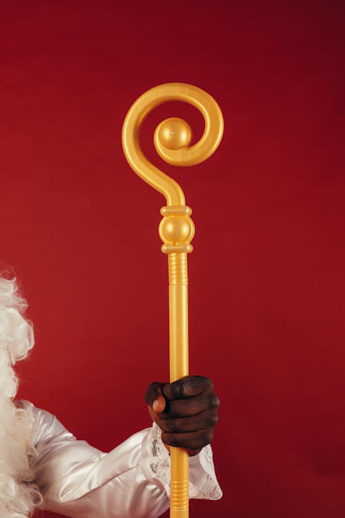 Person Holding a Yellow Staff on Red Background