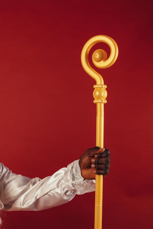 Person Holding a Yellow Staff on Red Background