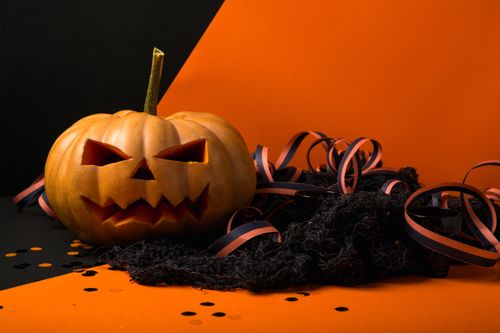 Free Spooky carved pumpkin with black and orange ribbon, perfect for Halloween decor. Stock Photo