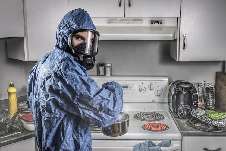 Male Chemist In Protective Respirator And Suit In Kitchen