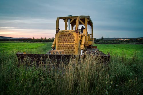 Tractor with in grassy field in countryside